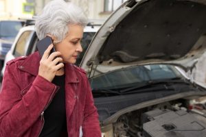 elegante-femme-mure-aux-cheveux-gris-attrayante-debout-pres-sa-voiture-blanche-cassee-capot-ouvert-parler-au-telephone